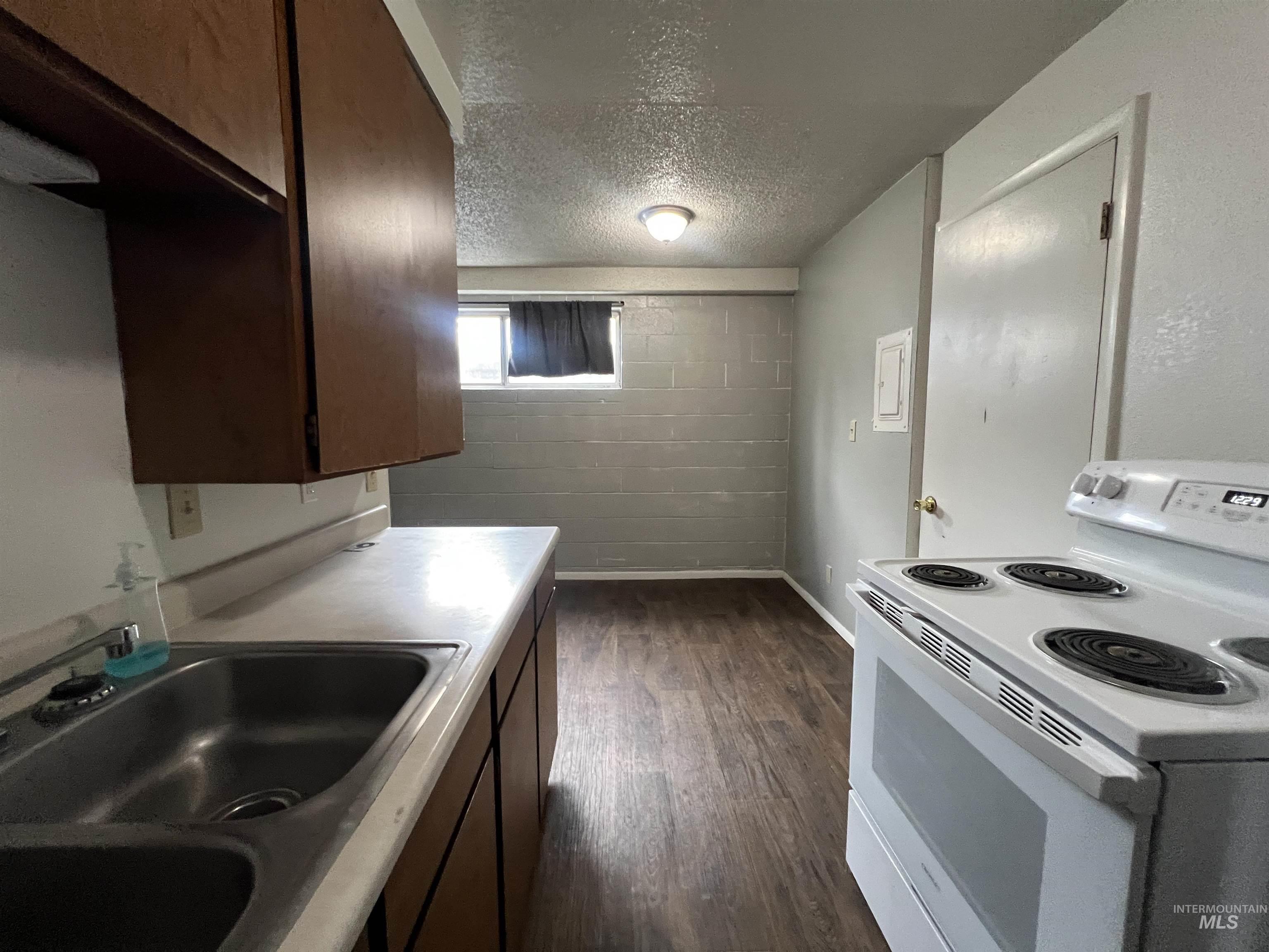 151 Northwest 8th Street Ontario, OR 97914 - Photo 24 of 30 Kitchen with white electric range oven, a textured ceiling, dark brown cabinetry, light countertops, and dark wood-style flooring