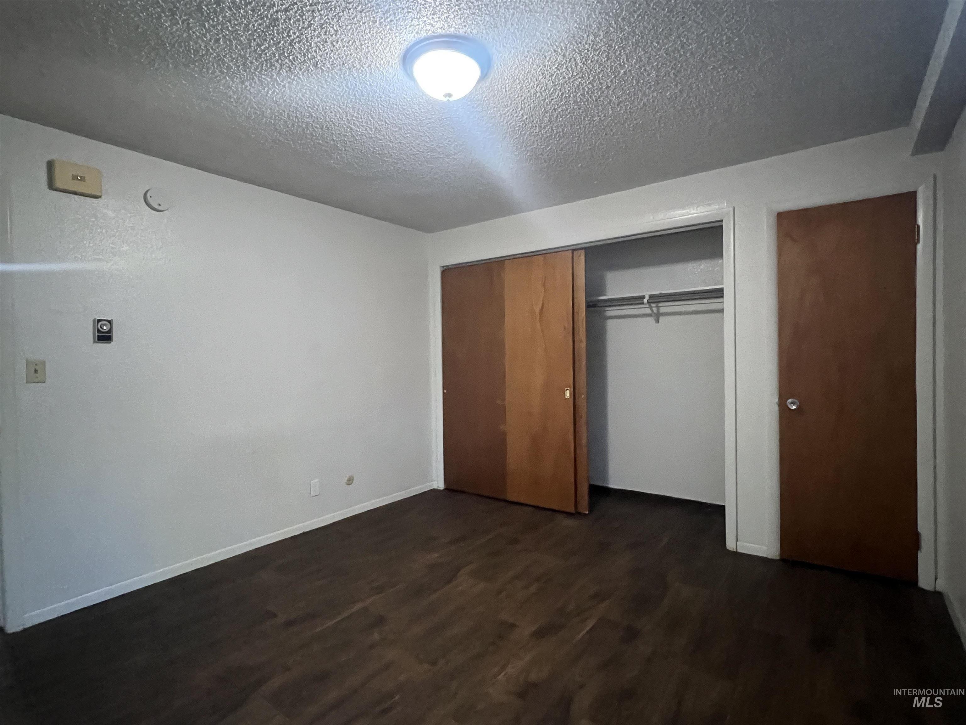 151 Northwest 8th Street Ontario, OR 97914 - Photo 29 of 30 Unfurnished bedroom with dark wood-style floors, a closet, and a textured ceiling