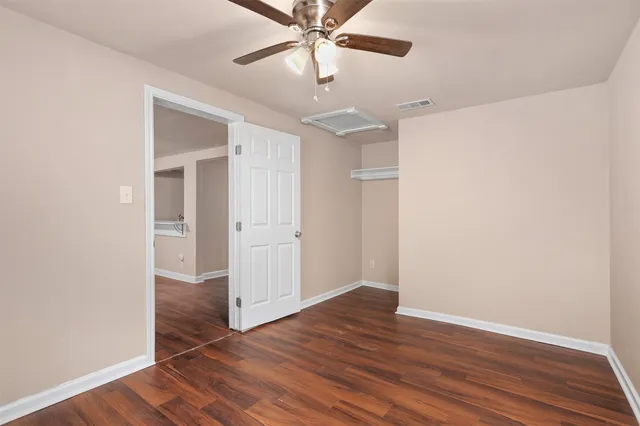 an empty room with wooden floor fan and windows