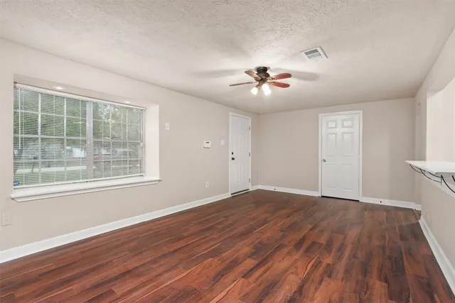 a view of an empty room with a window and wooden floor