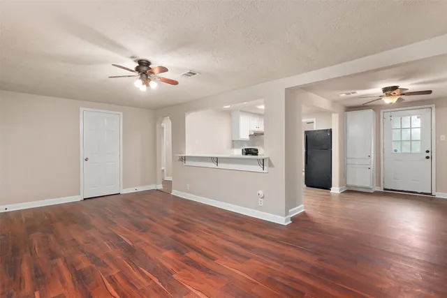 a view of a big room with wooden floor and a kitchen