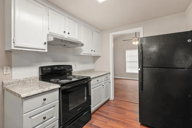 a kitchen with cabinets appliances and wooden floor