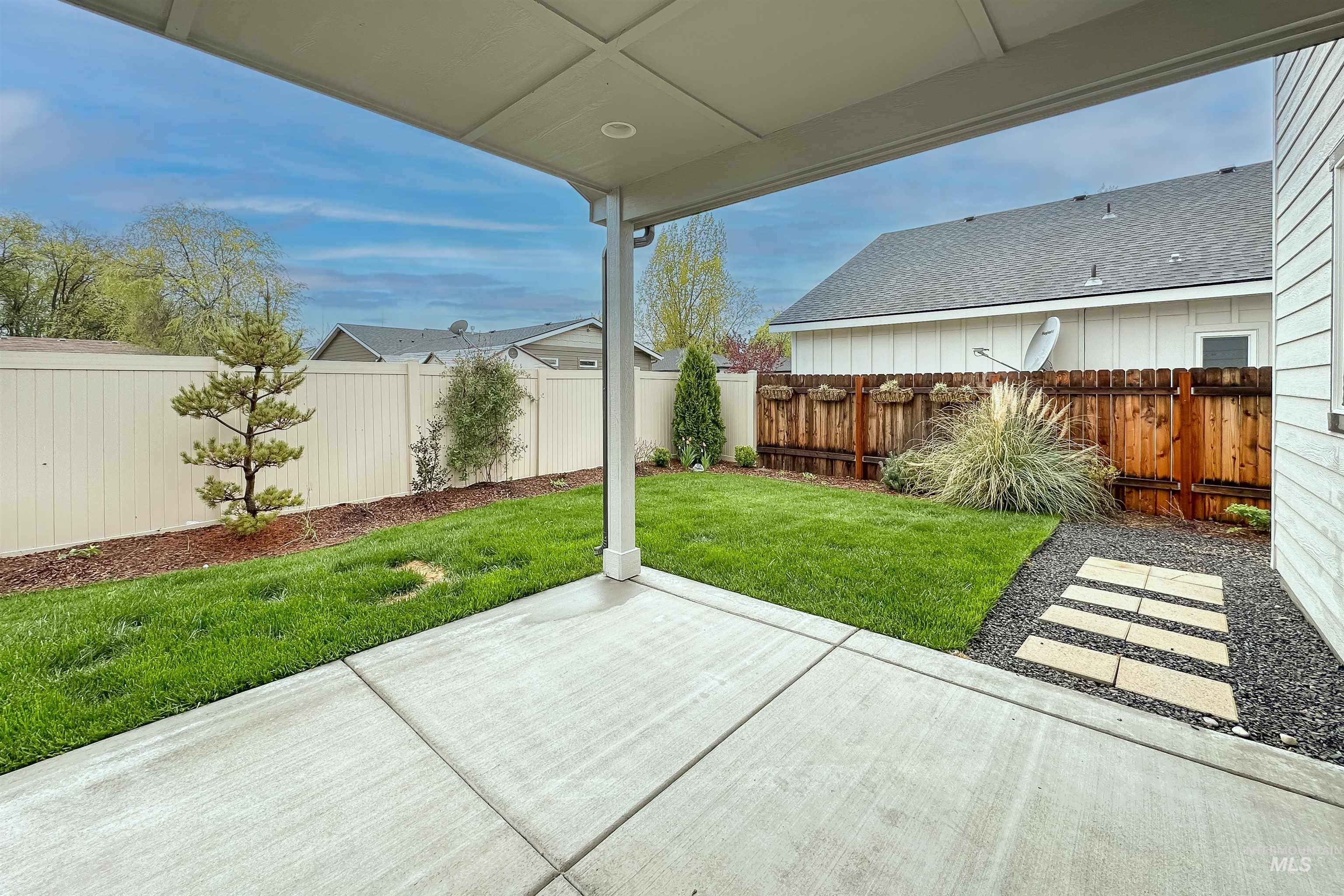9687 West Arnold Road Boise, ID 83714 - Photo 35 of 37 Covered concrete patio with a manicured lawn, established landscaping, and a stepping stone path