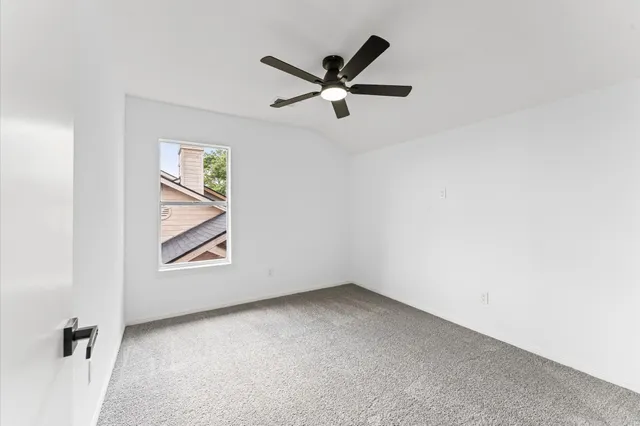 an empty room with windows and ceiling fan