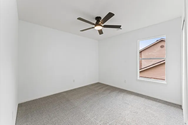 an empty room with window and ceiling fan