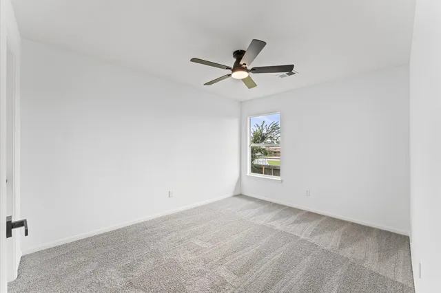 an empty room with a window and a fan