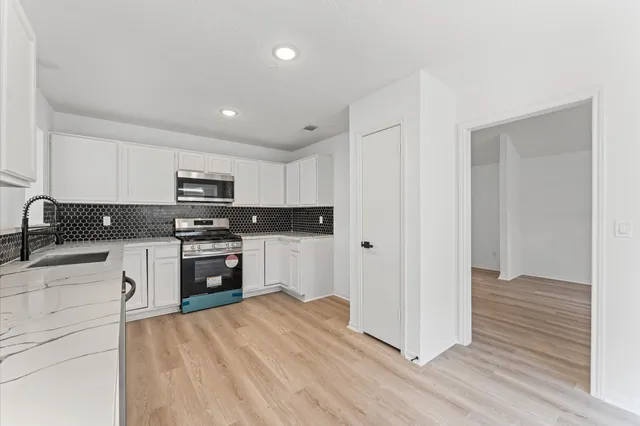 a kitchen with granite countertop white cabinets and stainless steel appliances