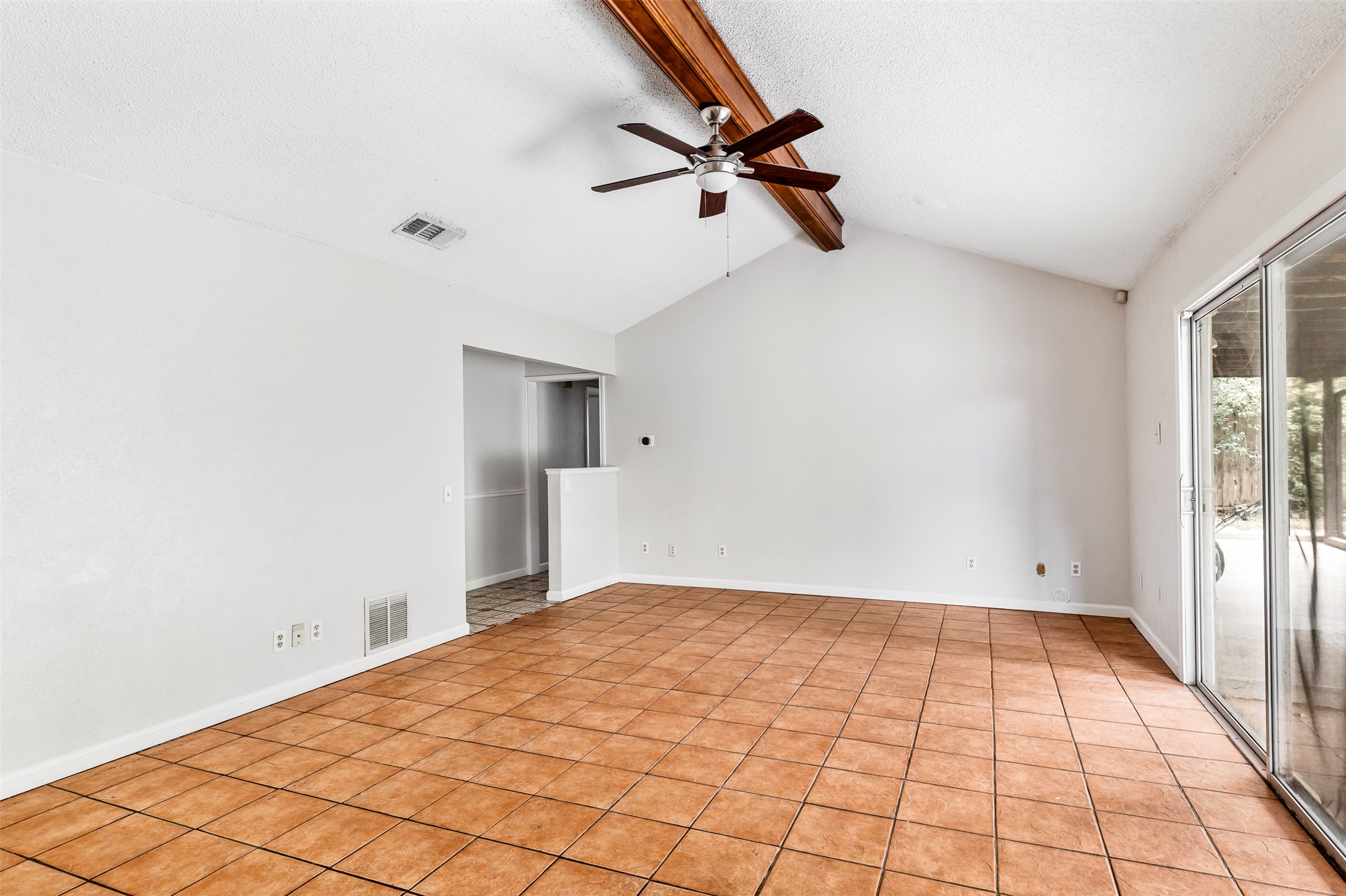 7506 Glenhill Road Austin, TX 78752 - Photo 9 of 24 Vast tile flooring enhances this spacious living area with vaulted ceilings and a ceiling fan.