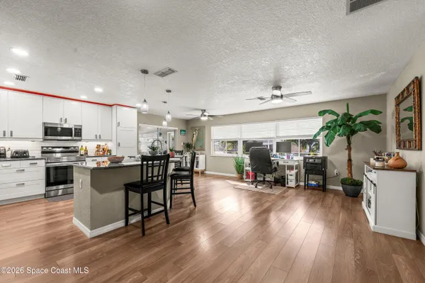 a kitchen with stainless steel appliances a dining table chairs stove and white cabinets