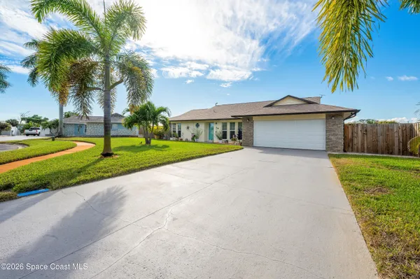 a front view of a house with a yard and palm trees
