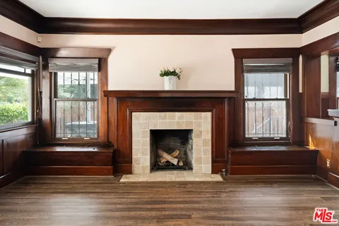 a living room with a fireplace windows and a ceiling fan