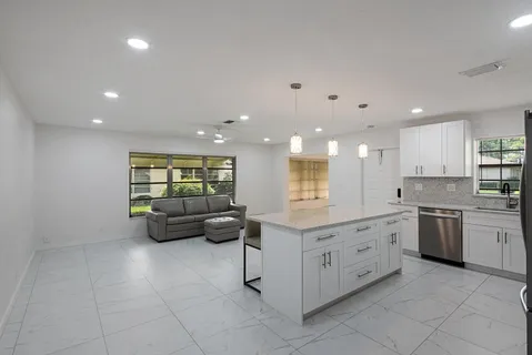a large white kitchen with stainless steel appliances granite countertop lots of white cabinets