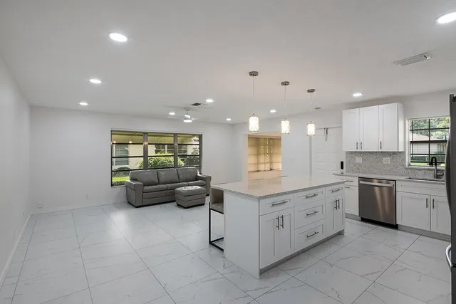 a large white kitchen with stainless steel appliances granite countertop lots of white cabinets