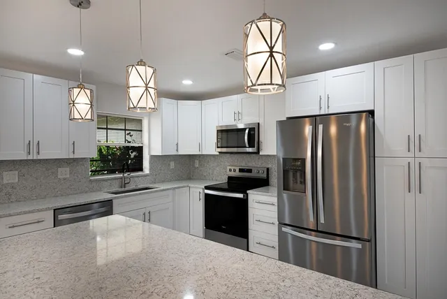 a kitchen with granite countertop a refrigerator a sink and dishwasher