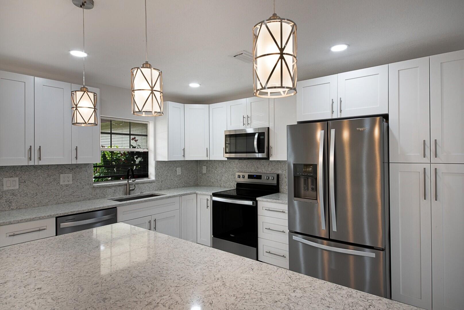 5220 Nesting Way, Unit D Delray Beach, FL 33484 - Photo 13 of 29 a kitchen with granite countertop a refrigerator a sink and dishwasher