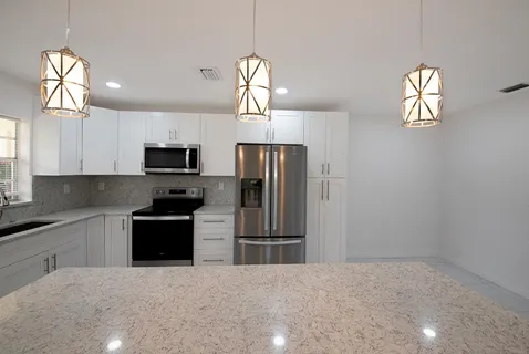 a kitchen with stainless steel appliances granite countertop a refrigerator a stove a sink and a window