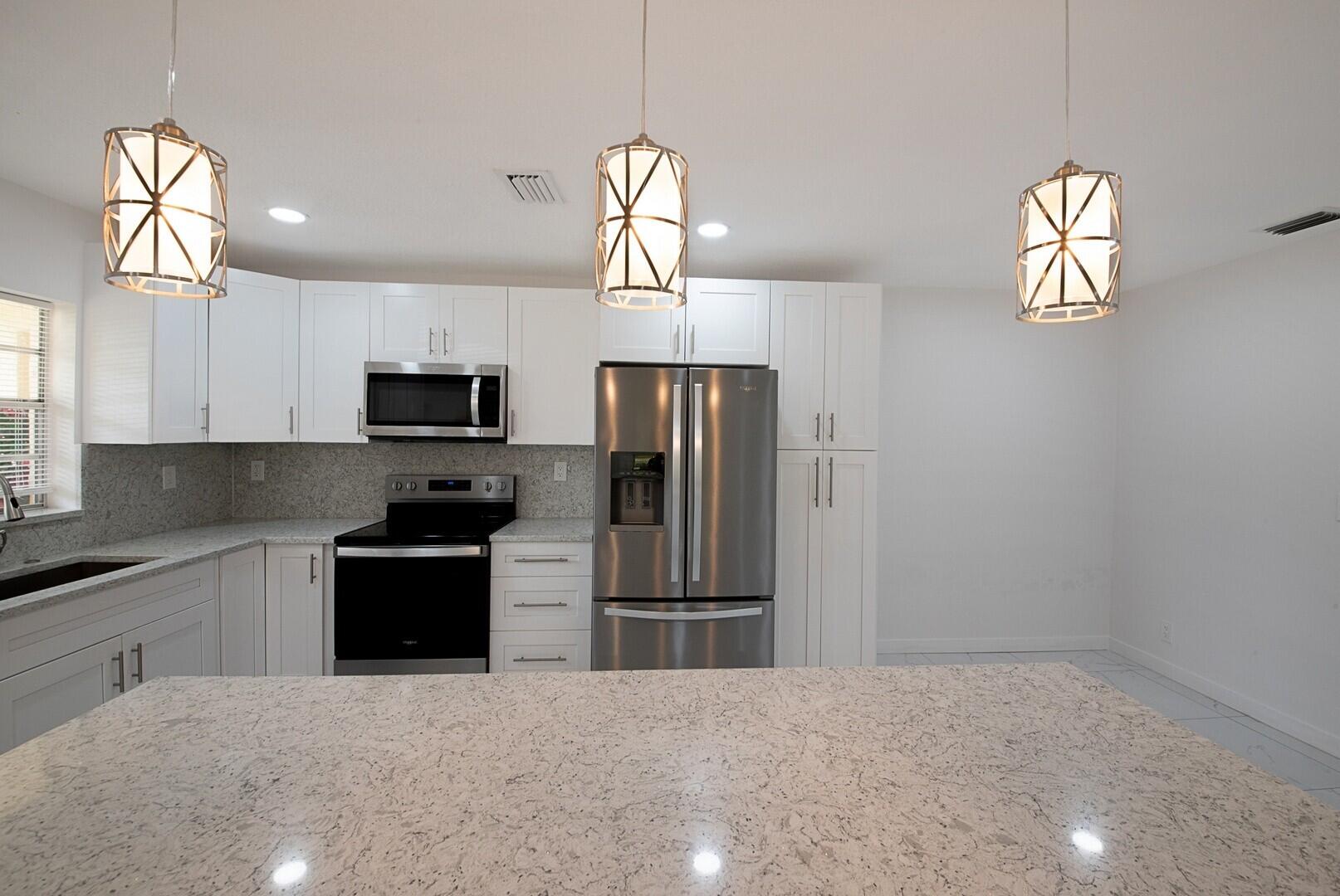 5220 Nesting Way, Unit D Delray Beach, FL 33484 - Photo 15 of 29 a kitchen with stainless steel appliances granite countertop a refrigerator a stove a sink and a window