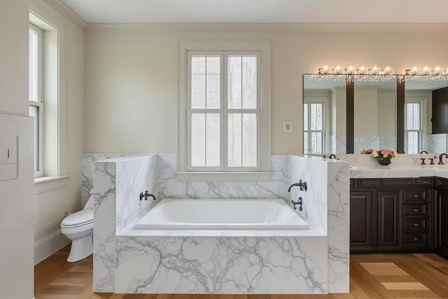 a spacious bathroom with a tub sink and mirror