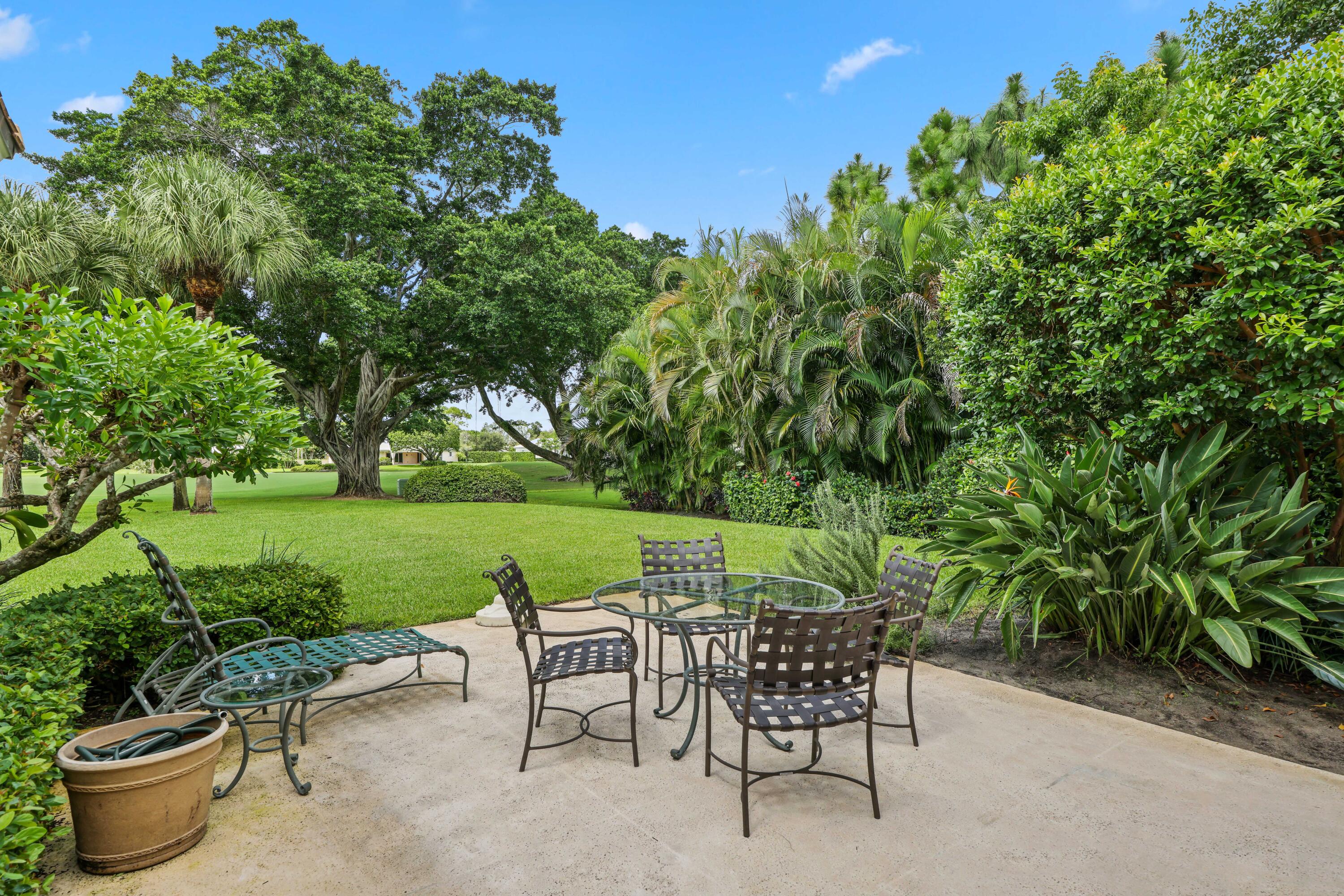 5 Country Road East, Unit A Boynton Beach, FL 33436 - Photo 48 of 51 a view of a patio with table and chairs potted plants and palm tree