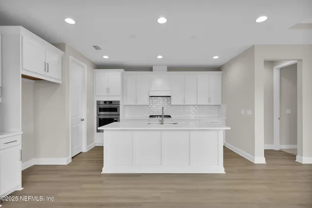 a large kitchen with stainless steel appliances a sink a refrigerator and a stove