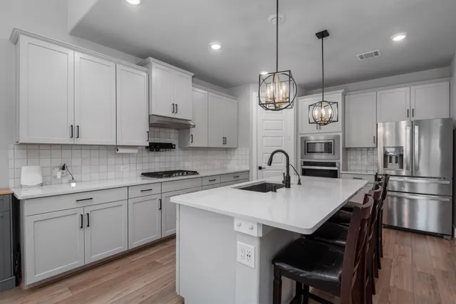 a kitchen with stainless steel appliances granite countertop a sink a stove a refrigerator and cabinets