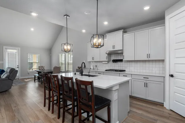 a kitchen with cabinets wooden floor dining table and stainless steel appliances