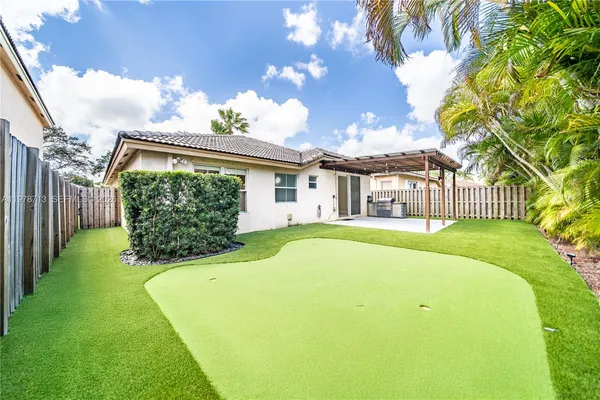 a view of a white house with a large trees and plants