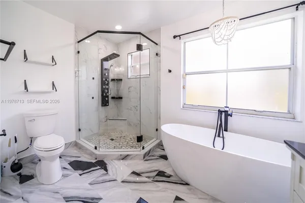 a white bath tub sitting next to a white toilet and a shower
