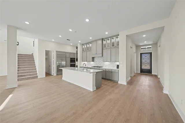 a large white kitchen with kitchen island a sink stainless steel appliances and cabinets