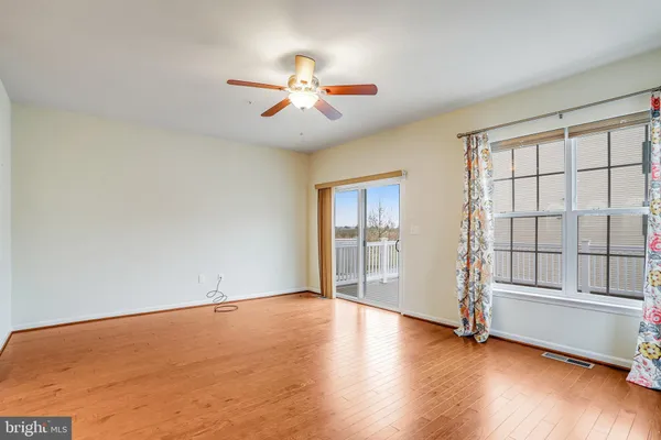 an empty room with wooden floor fan and windows