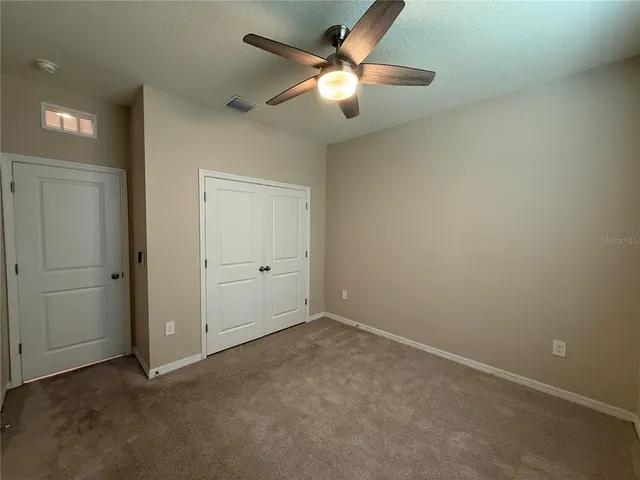 an empty room with closet and a chandelier fan