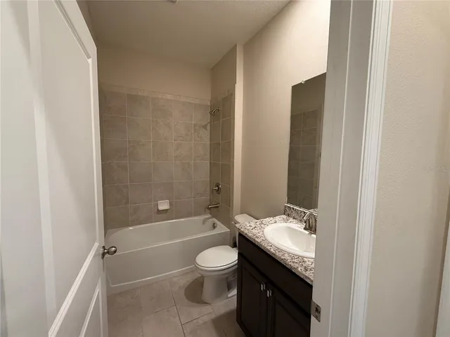 an empty room with chandelier fan and windows