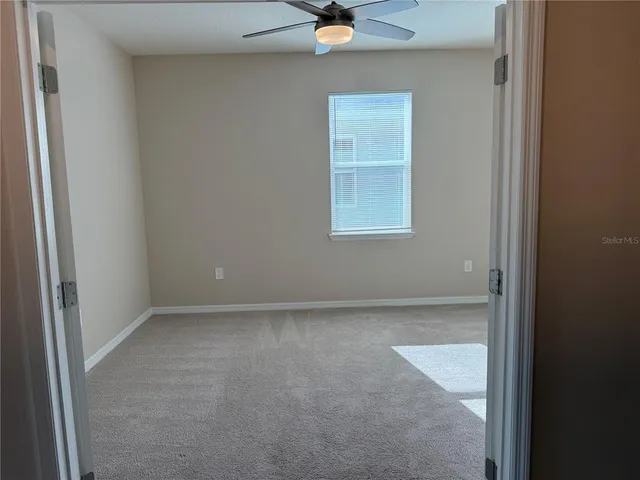 an empty room with a ceiling fan and a window