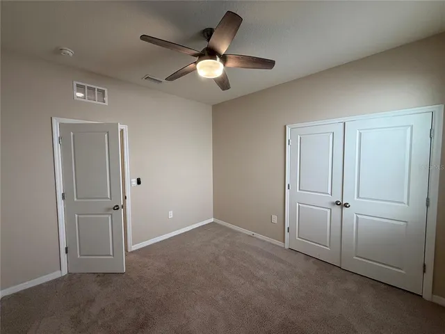 an empty room with a ceiling fan and window