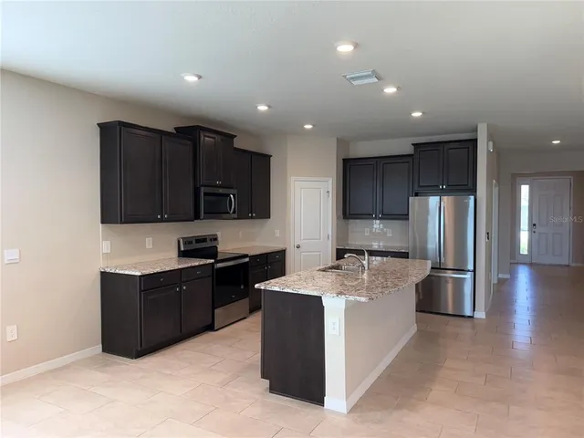 a kitchen with stainless steel appliances granite countertop a refrigerator stove a sink and a microwave