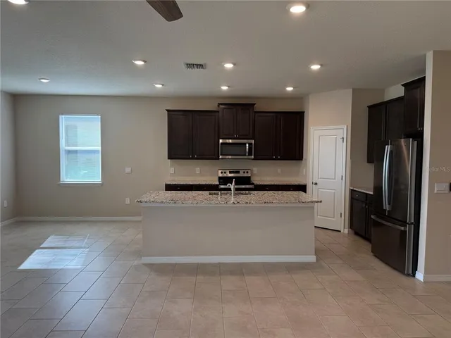 a large kitchen with stainless steel appliances granite countertop a refrigerator a sink a stove and cabinets