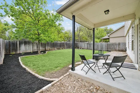 a view of a patio with a table chairs and a small yard