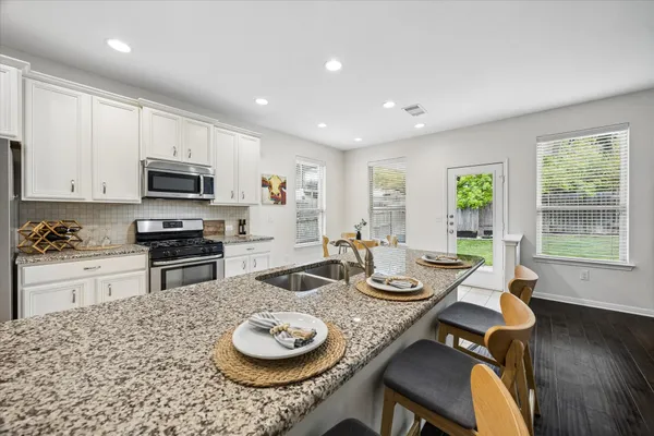 a kitchen with a stove a microwave a dining table and chairs