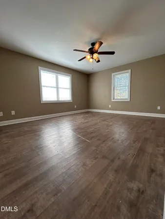 an empty room with windows and a ceiling fan