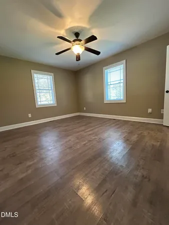 an empty room with wooden floor window and ceiling fan