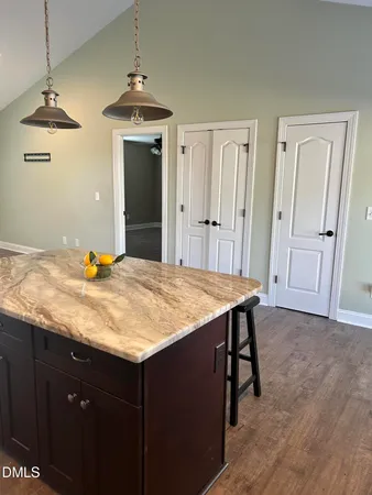 a room with kitchen island a sink dishwasher a dining table and chairs with wooden floor