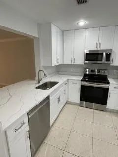 a kitchen with cabinets a sink and white appliances