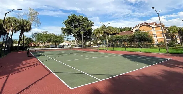 a view of a tennis ground with large trees