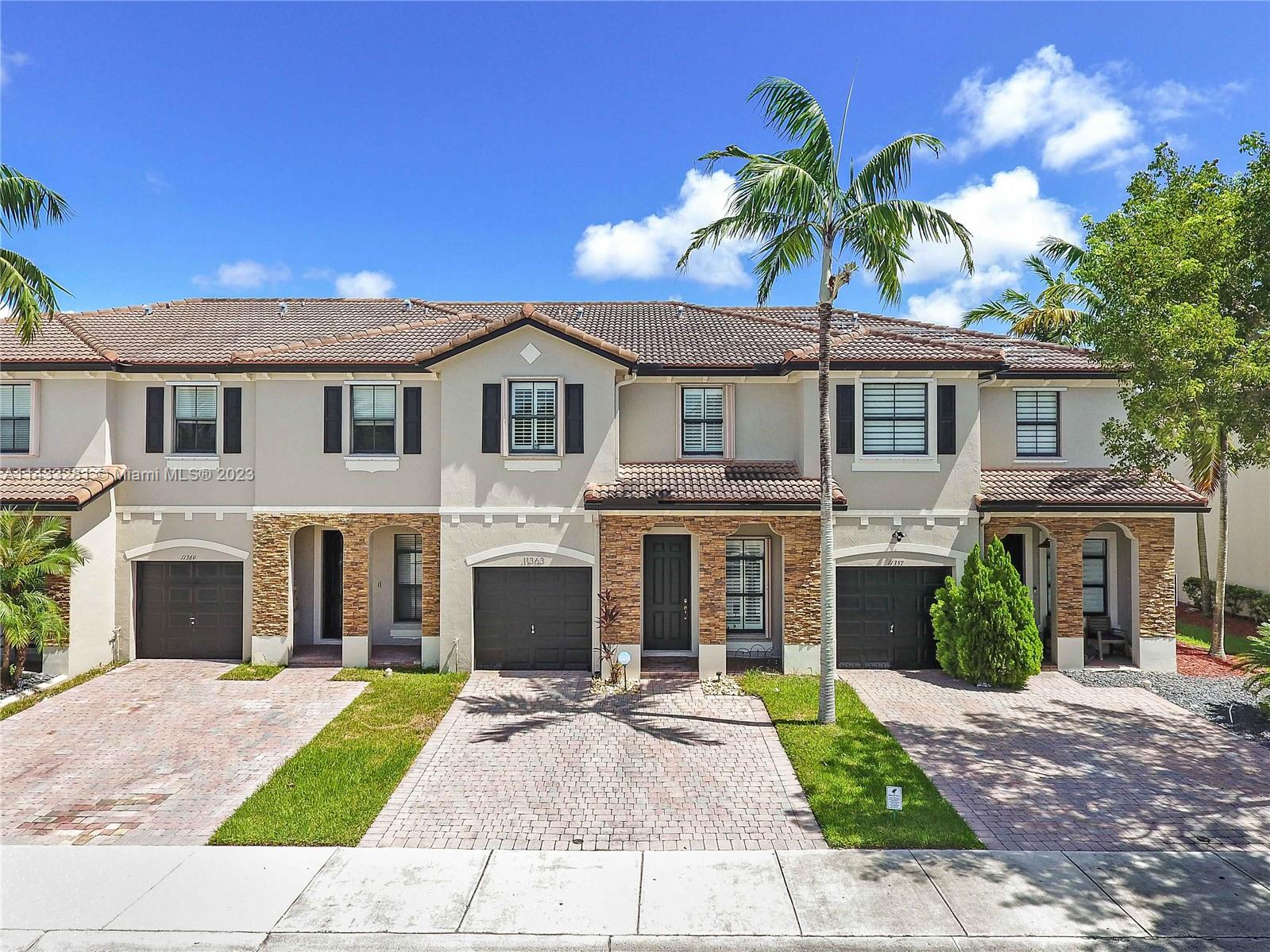 11363 Southwest 240th Street Homestead, FL 33032 - Photo 2 of 39 a front view of a house with a yard and garage