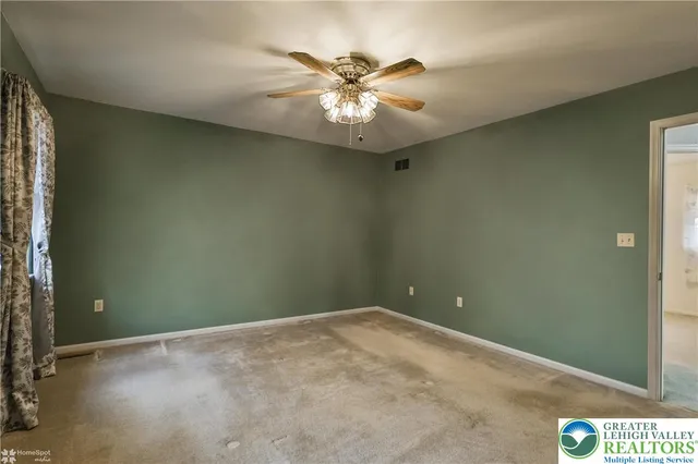an empty room with window and ceiling fan