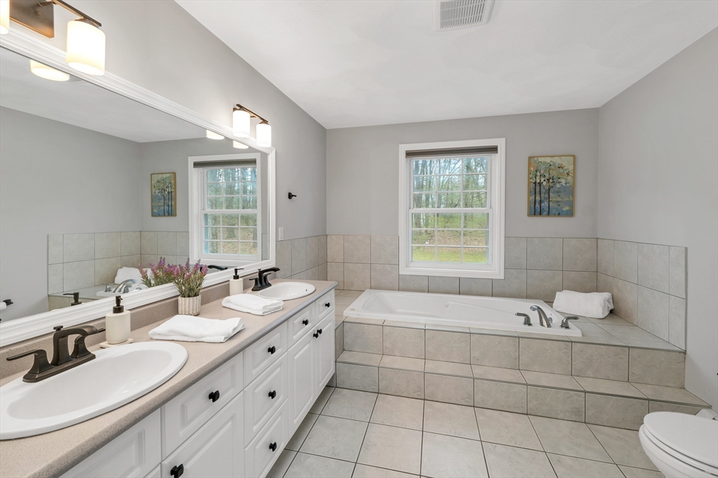 9 Juniper Ridge Road Exeter, NH 03833 - Photo 35 of 41 a bathroom with a double vanity sink large mirror and a bathtub