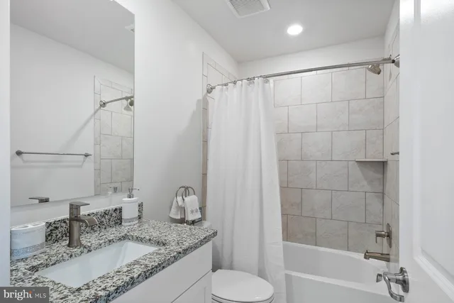 a bathroom with a granite countertop sink toilet and shower
