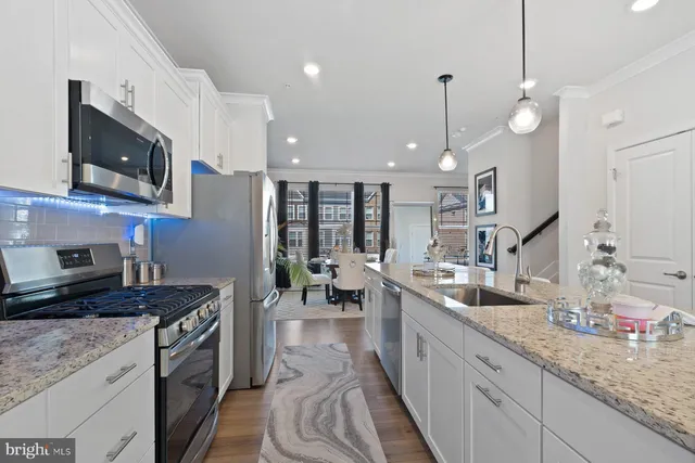 a kitchen with stainless steel appliances granite countertop a sink a stove top oven a counter space and cabinets