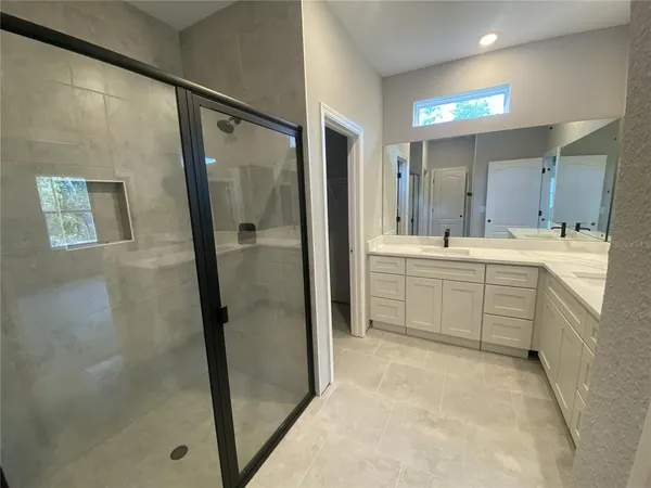 a bathroom with a double vanity sink a shower and a mirror