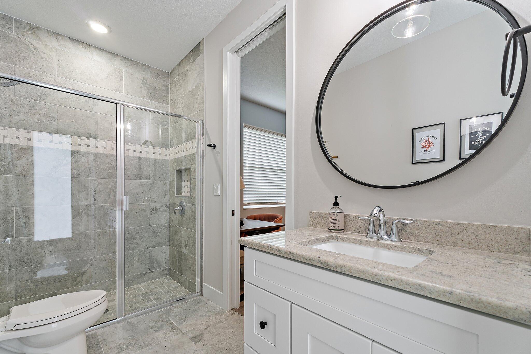 12216 175th Road North Jupiter, FL 33478 - Photo 35 of 57 a bathroom with a granite countertop sink a toilet a glass door a shower and a mirror